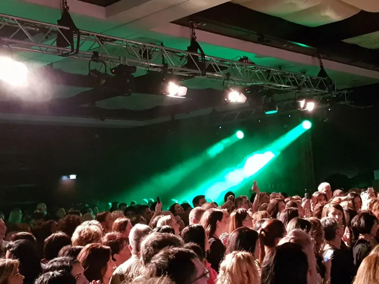 Sală plină la un eveniment de companie, cu efecte laser verzi
