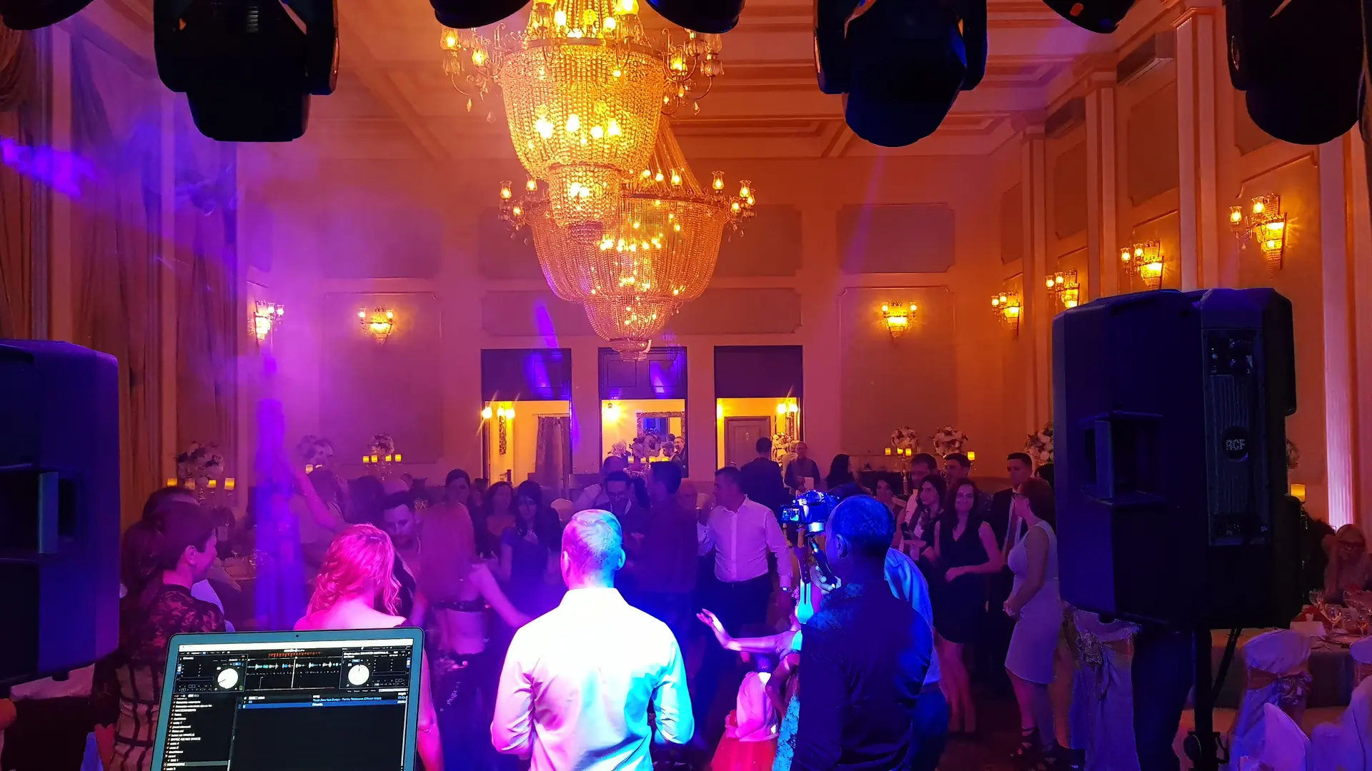 DJ PartyDJ la pupitru, ringul plin la o nuntă într-o sală de bal cu candelabre